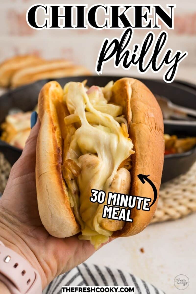 Chicken Philly sandwich in a hand with gooey, stringy cheese.