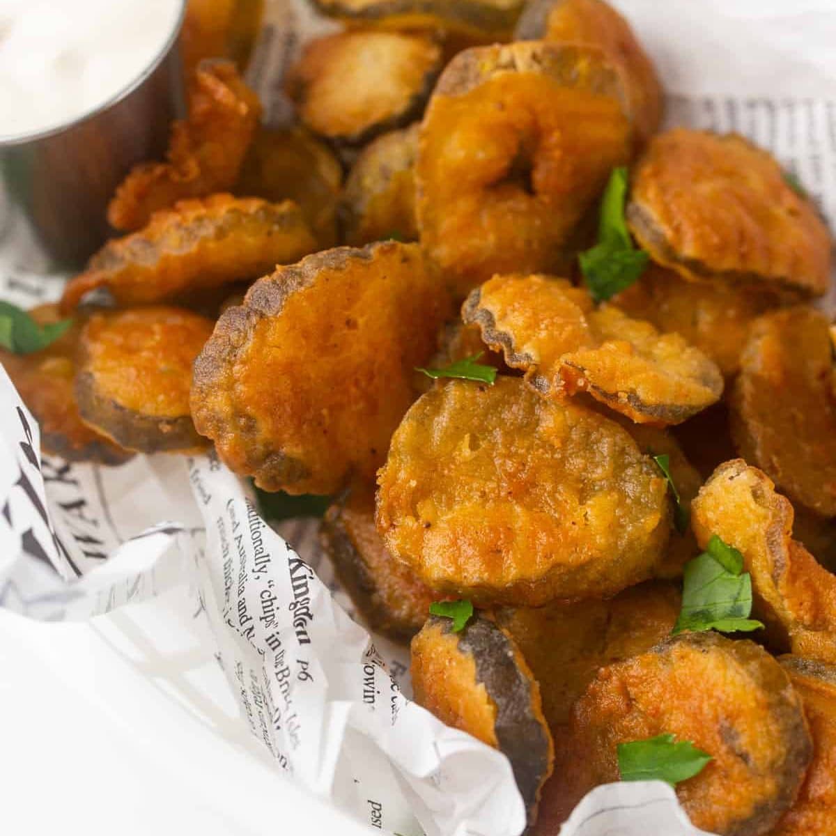 Deep fried pickles on a plate with dipping sauce.