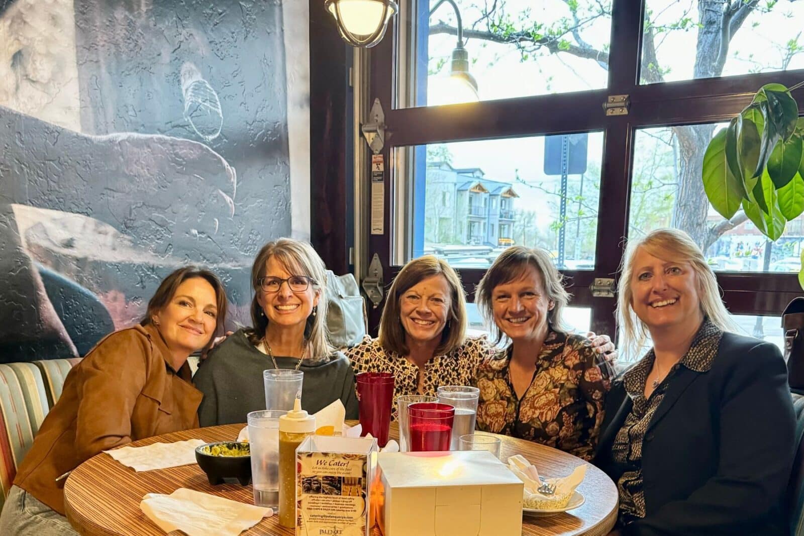 5 women sitting around a table at dinner.