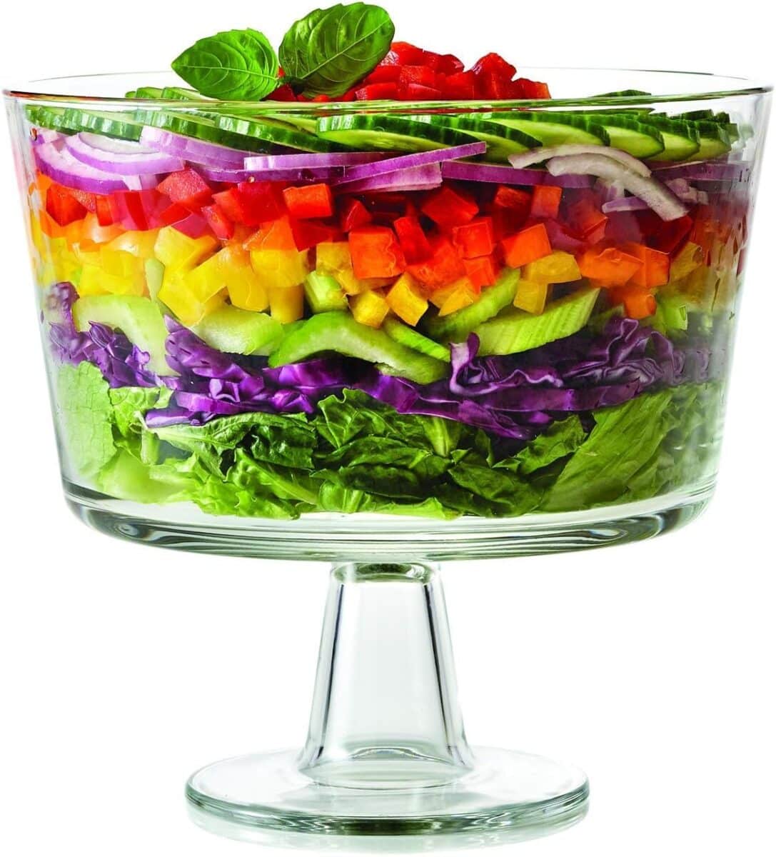 Glass trifle bowl, filled with layers of brightly colored salad ingredients. 