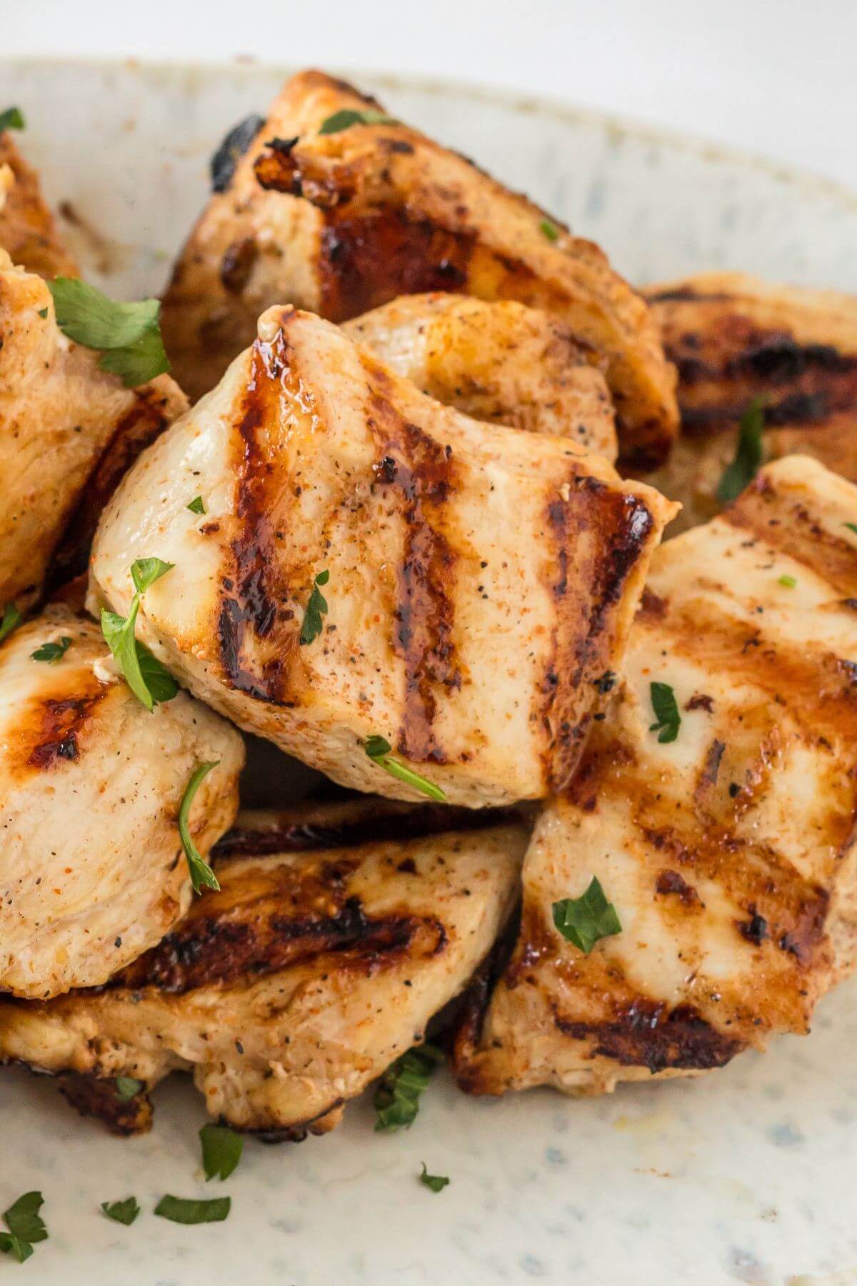 A pile of chicken chunks with grill marks rest on a plate.