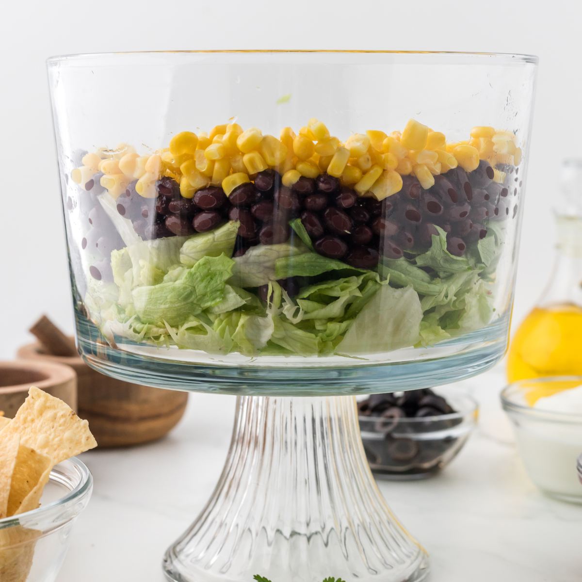 Layering the taco salad ingredients in a clear bowl. 