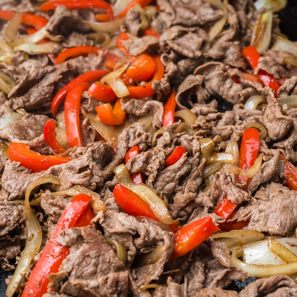 Onions and peppers mixed together on Blackstone griddle with shaved steak. 