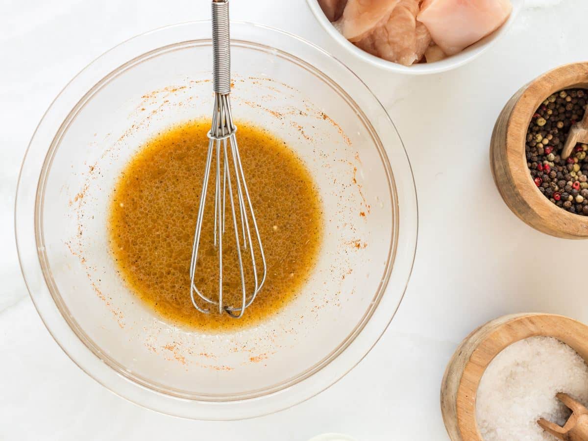 Marinade or brine ingredients in a glass bowl with raw chicken in background. 