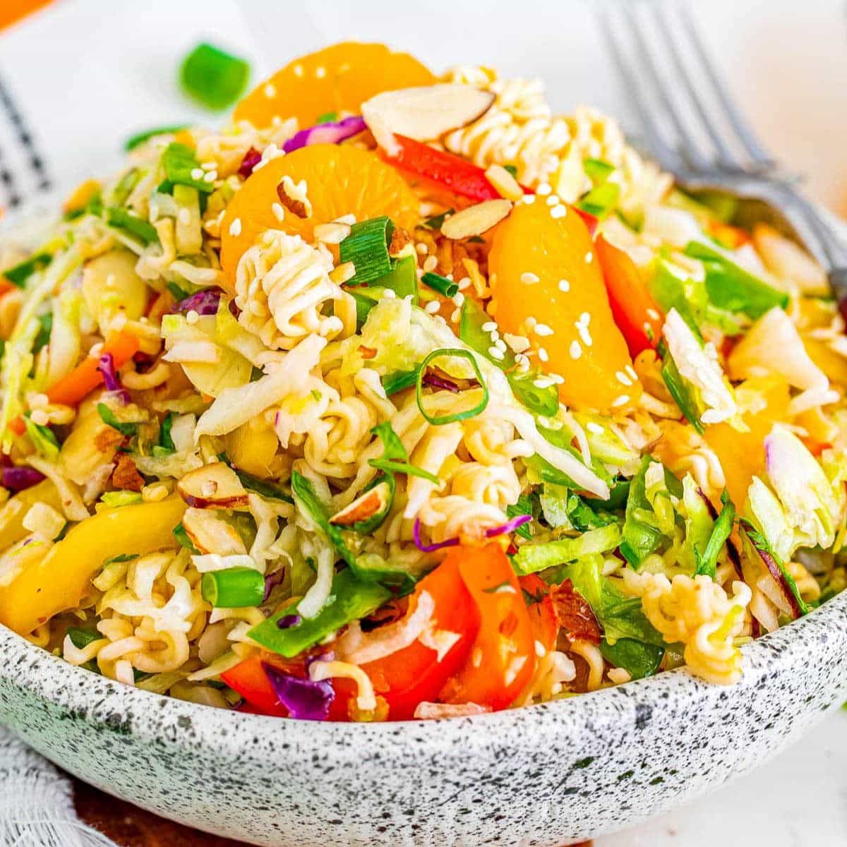 Ramen noodle salad with oranges and veggies in a pretty serving bowl.