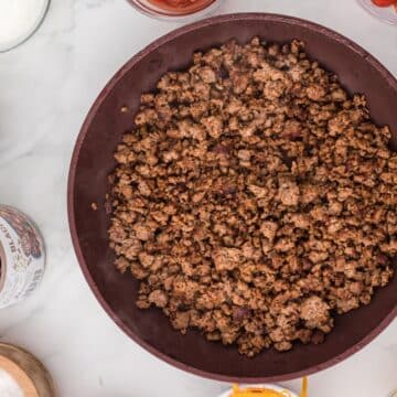 Browned and seasoned ground beef in a skillet.