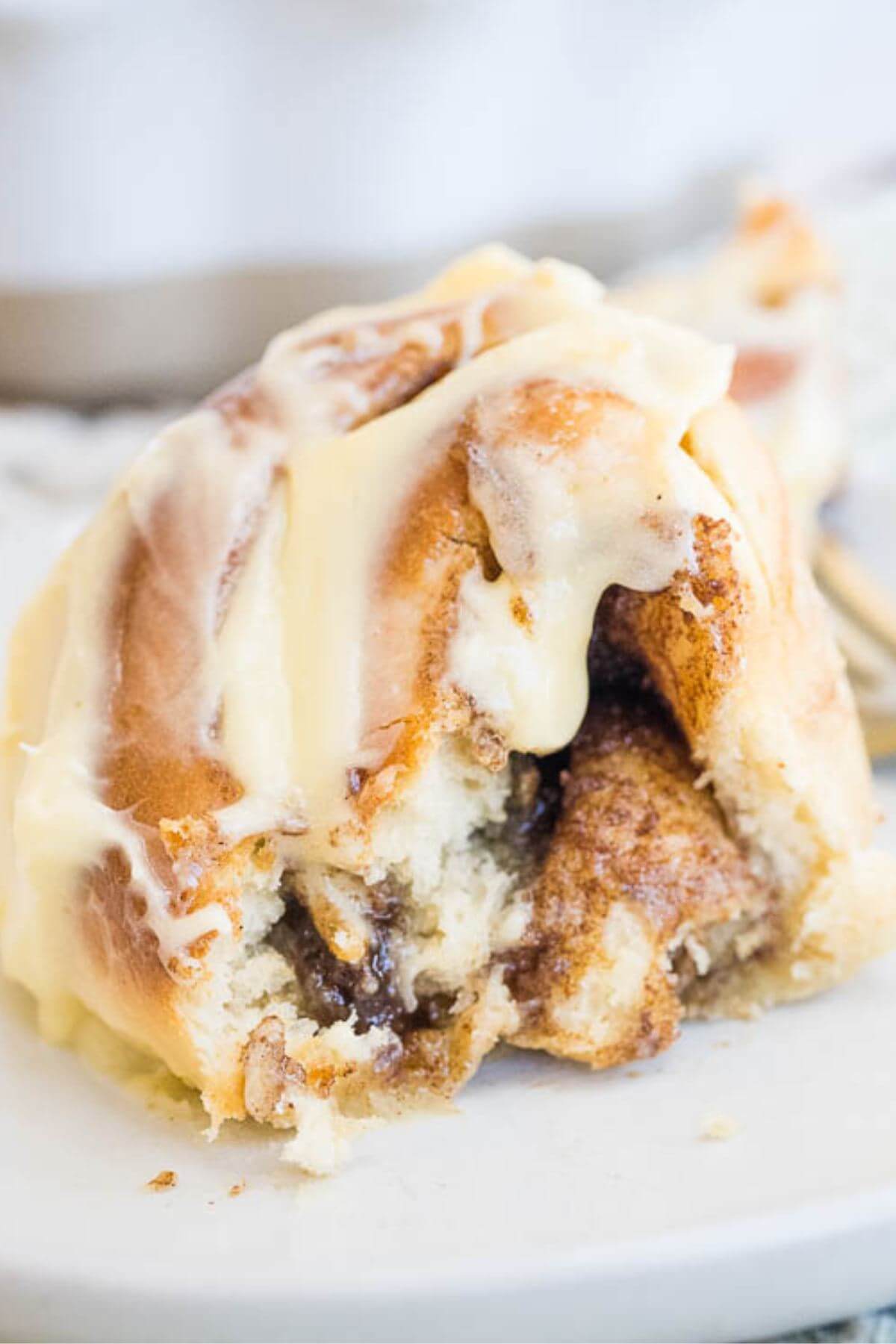 Half of a cinnamon bun shows the smooth cream cheese icing and gooey cinnamon filling inside.
