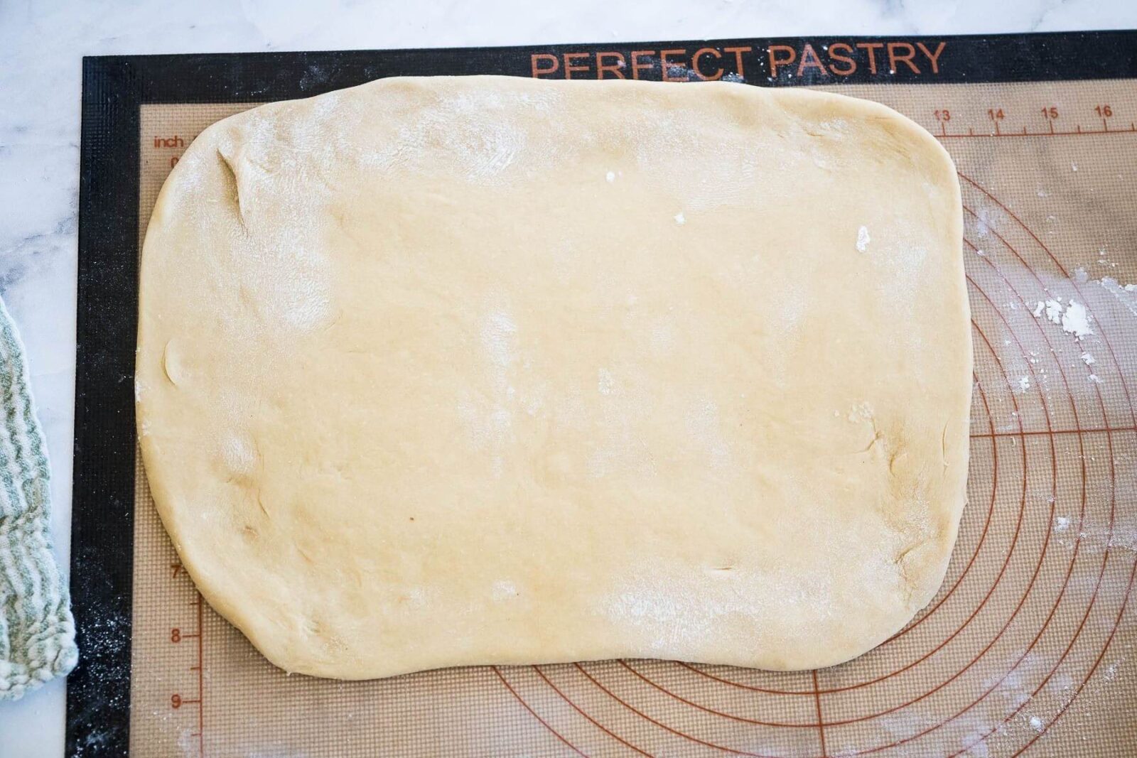 Dough is rolled flat on a rolling board.