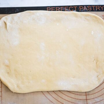 Dough is rolled flat on a rolling board.