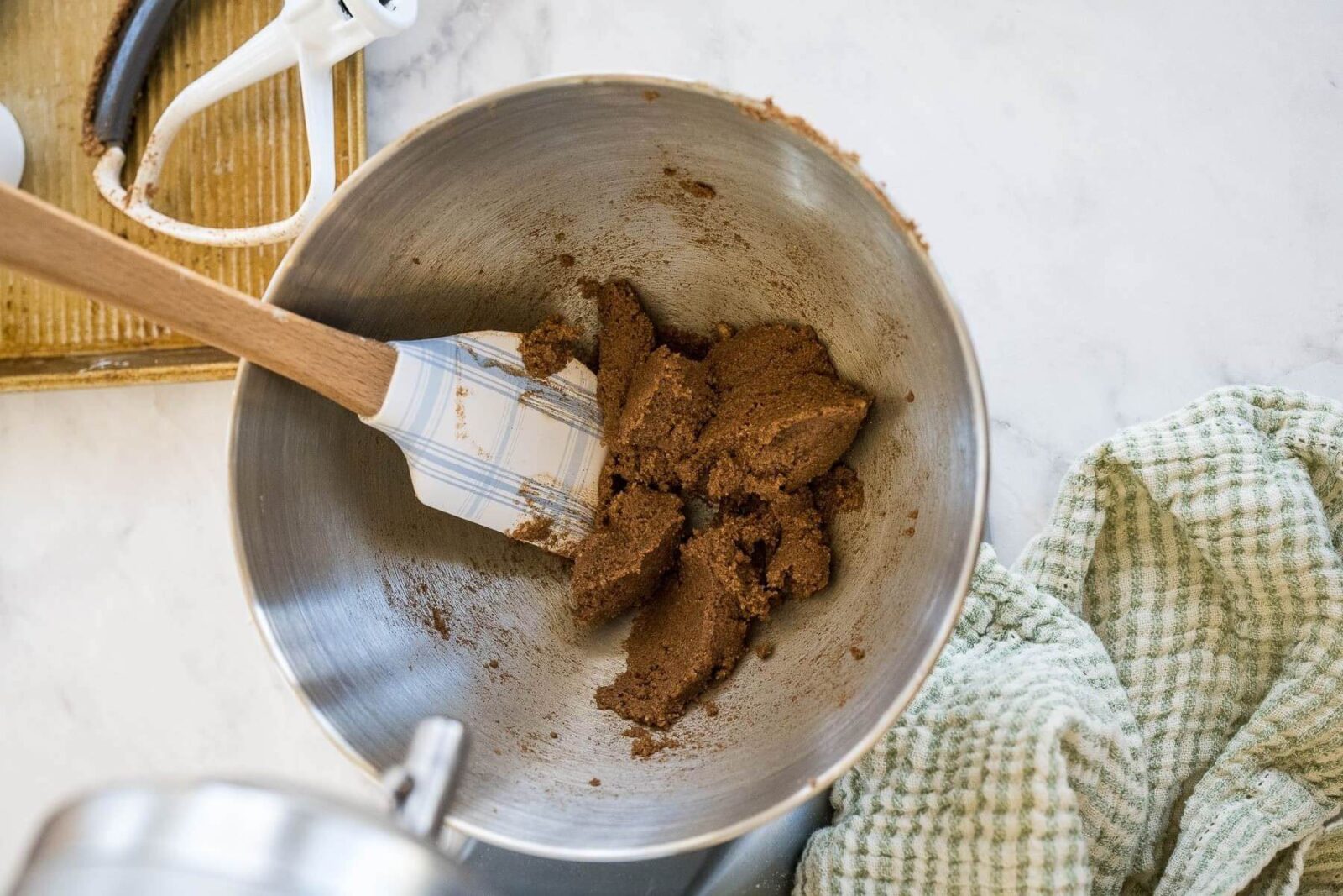 Packed brown sugar is in a metal mixing bowl with a spatula.