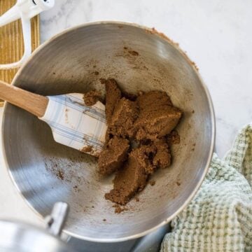Packed brown sugar is in a metal mixing bowl with a spatula.