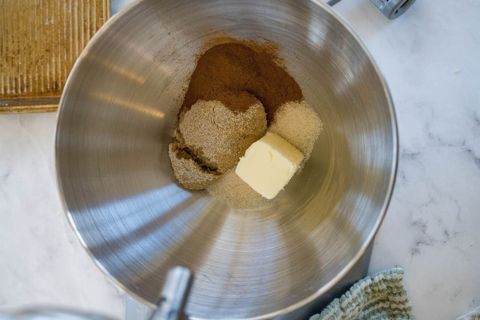 Packed brown sugar, cinnamon, butter, and salt is in a metal bowl of a stand mixer.