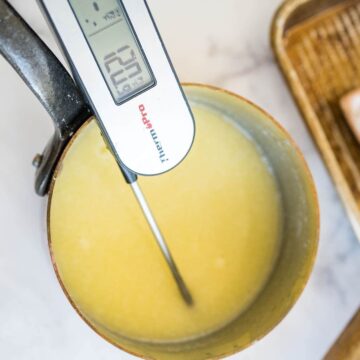 A food thermometer measures a melted butter mixture in a saucepan reading 120 degrees.