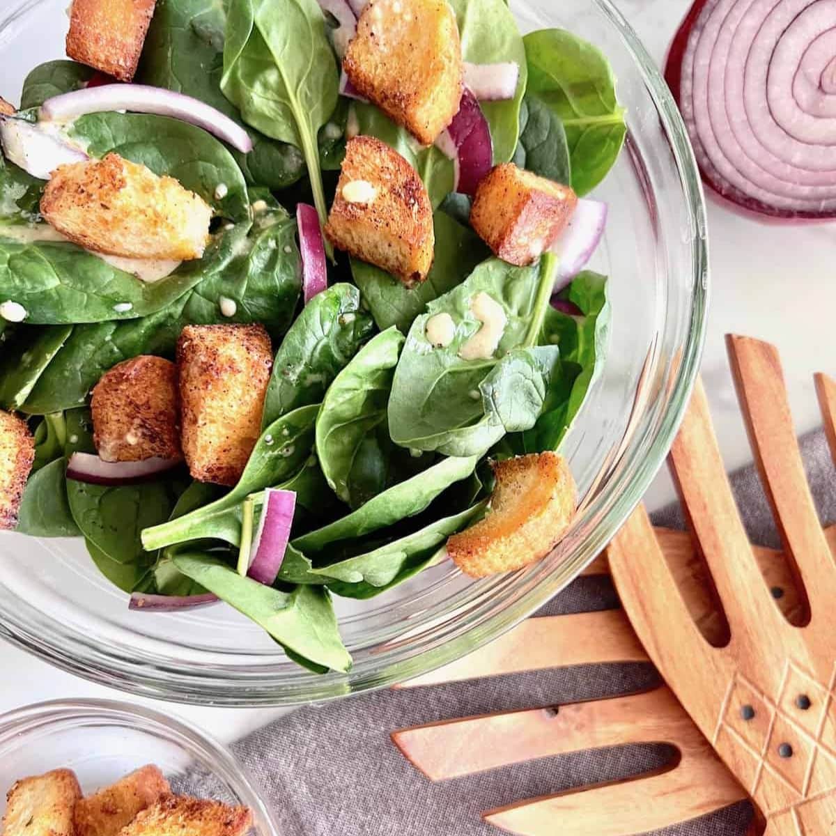 Spinach salad with serving spoons.