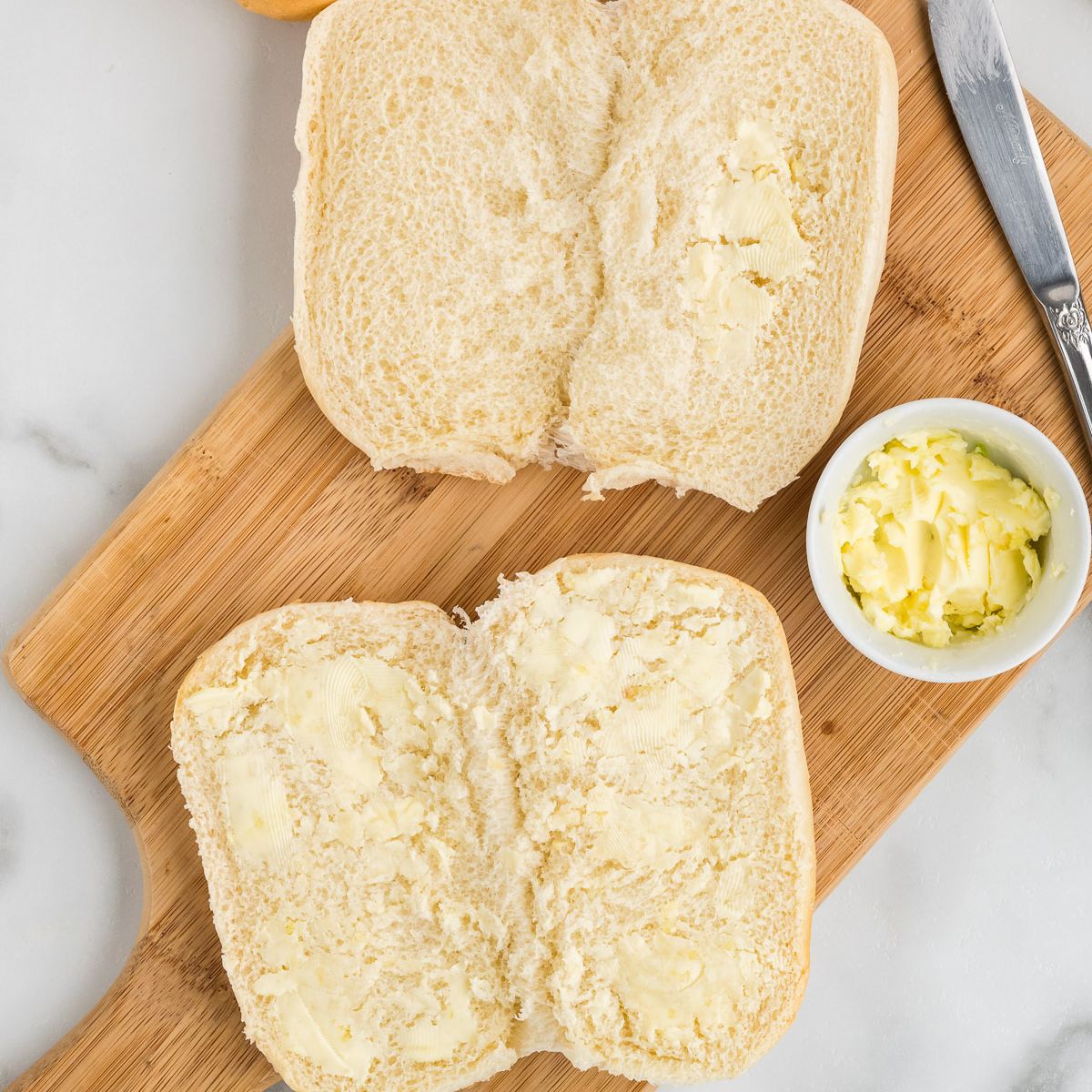 Spread garlic butter onto rolls.