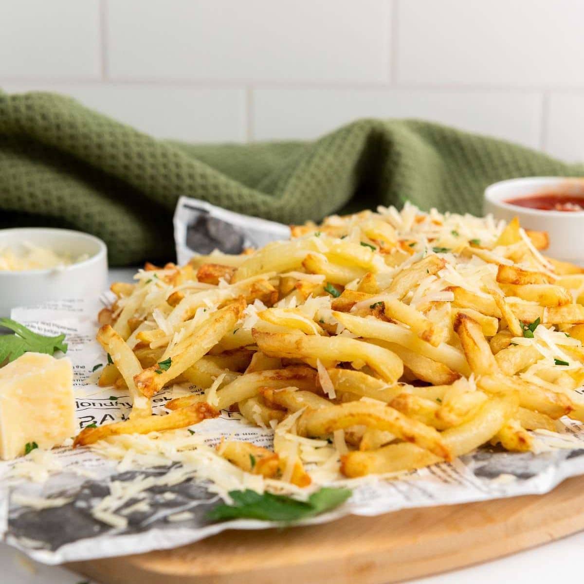 A pile of crispy air fryer truffle and parmesan fries on newspaper.