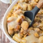 Cinnamon roll bread pudding in baking casserole dish with spoon serving.