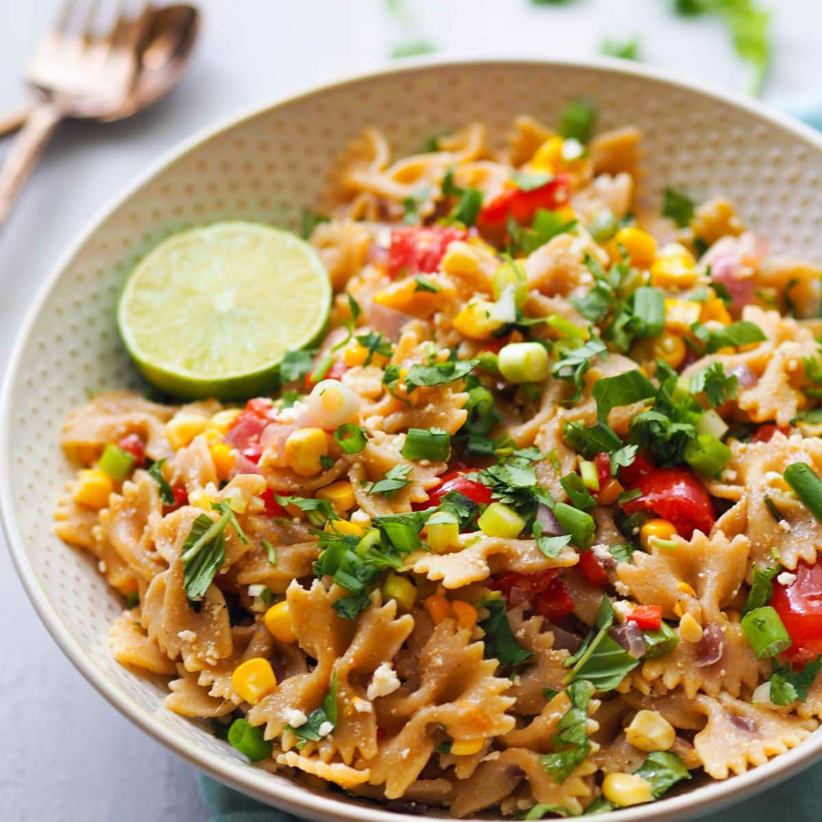 A large bowl filled with bow tie pasta, an herbed summer corn pasta salad.