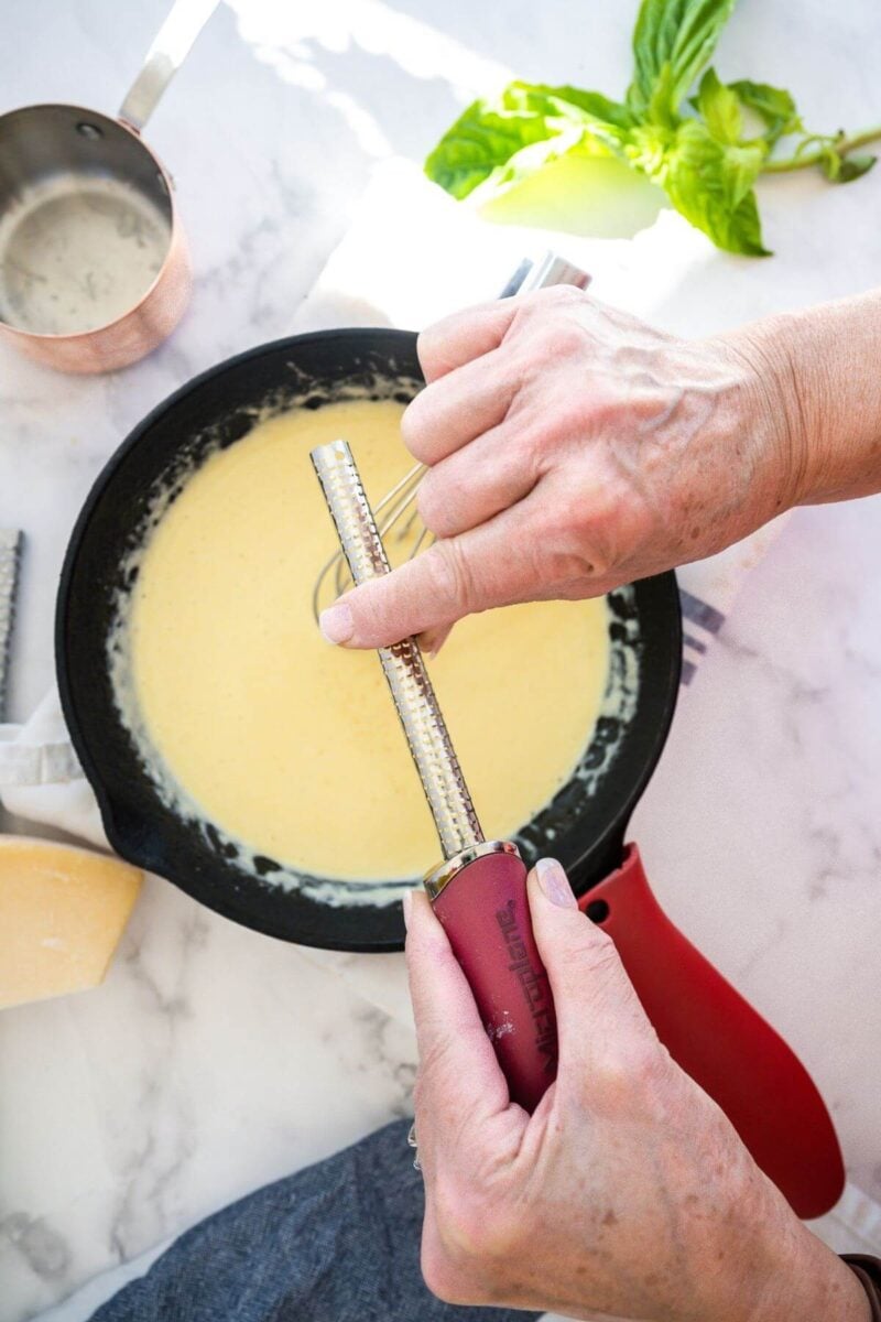 Grating in fresh nutmeg into alfredo sauce for stuffed shells.