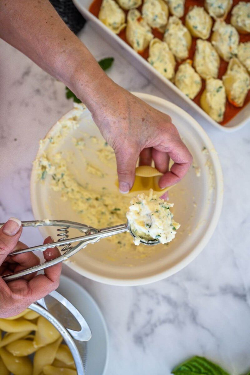 Filling cooked shells with Italian ricotta cheese mixture.