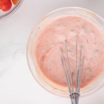 Bowl filled with salsa mixed sour cream with whisk.