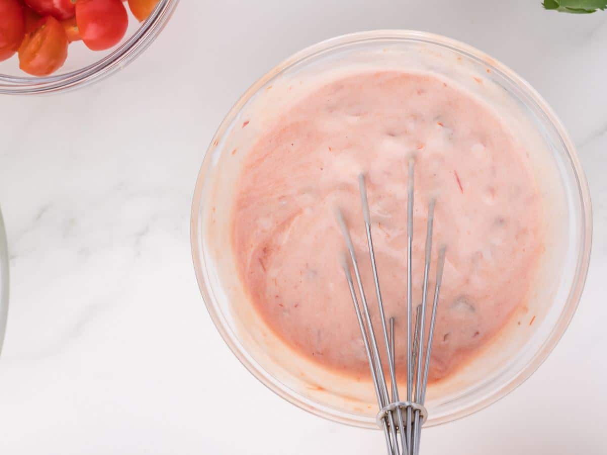 Bowl filled with salsa mixed sour cream with whisk.