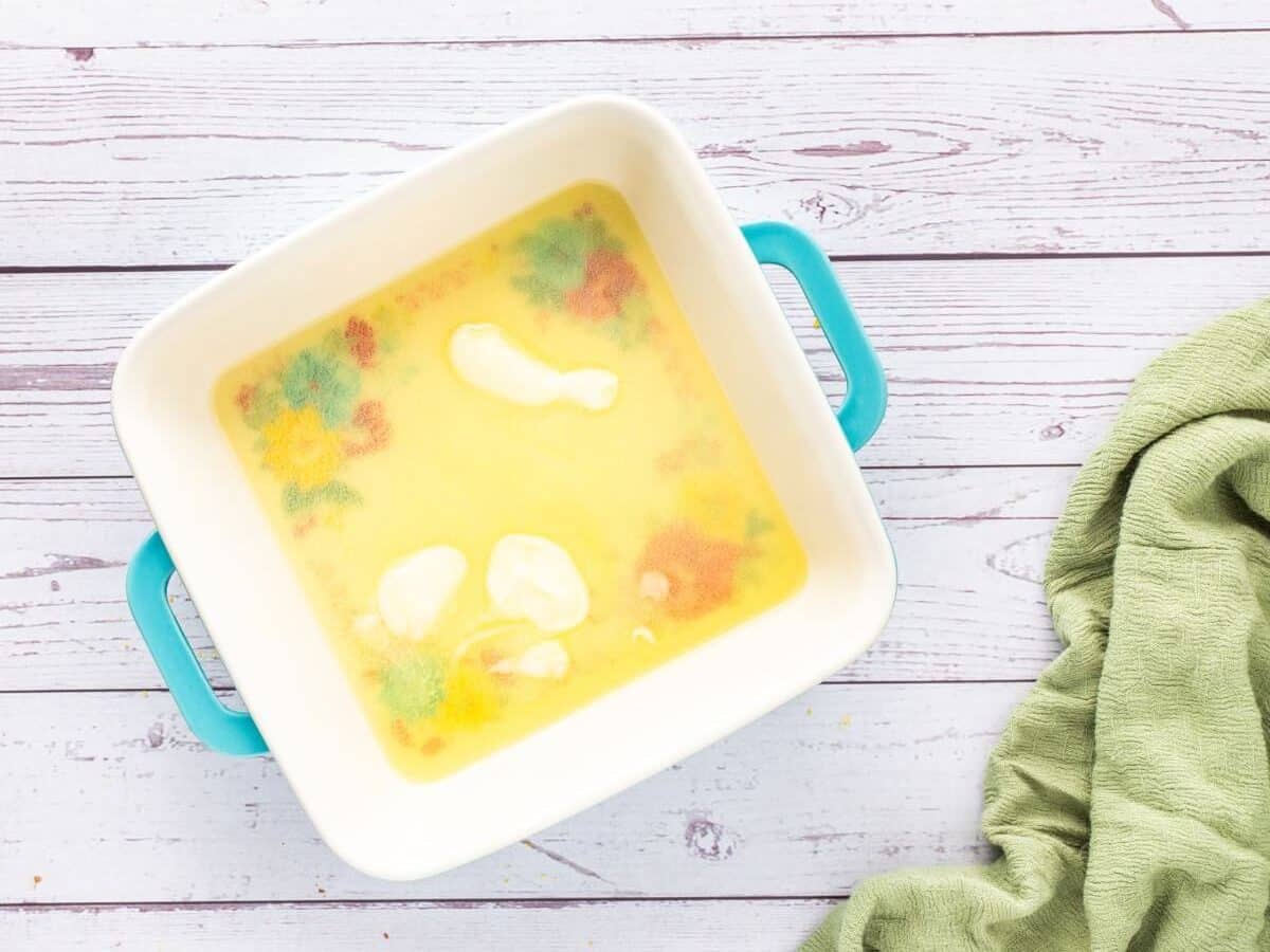 Melted butter rests in the bottom of a square pan.