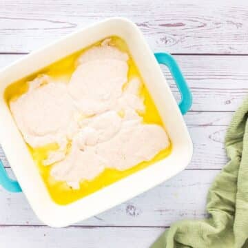 Unbaked batter sits in globs on top of melted butter in a pan.