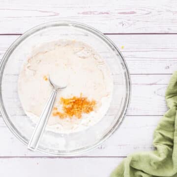 A glass bowl with a spoon inside mixes together ingredients.