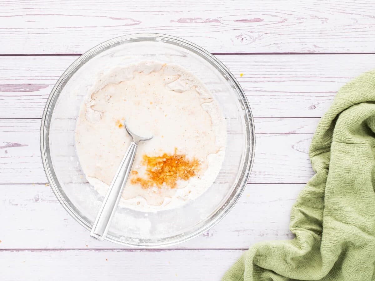 A glass bowl with a spoon inside mixes together ingredients.