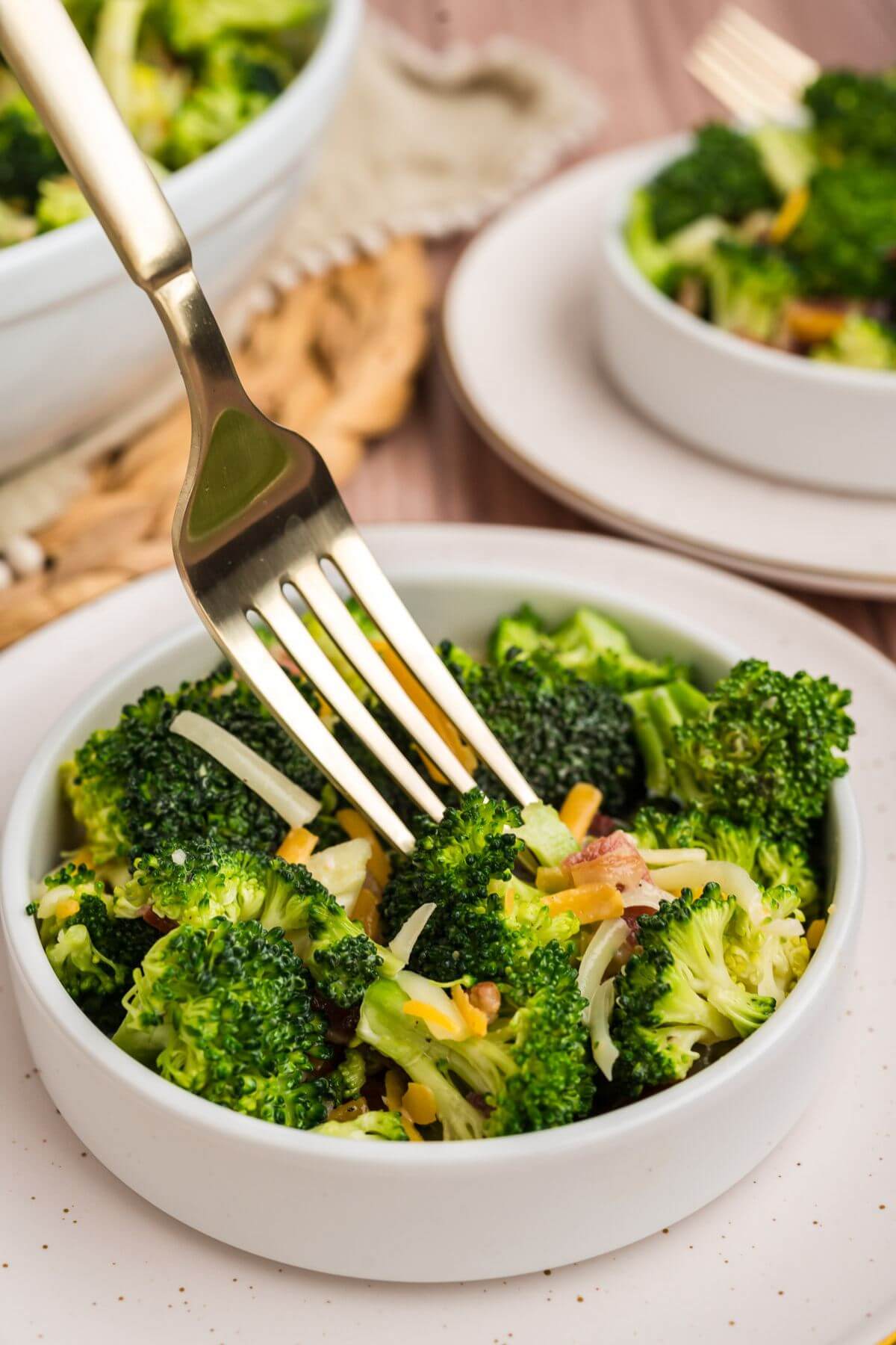 A metal fork dives into a small serving bowl of salad.