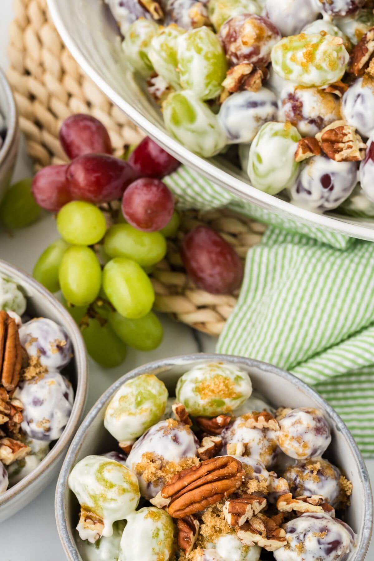 Red and green grape clusters sit between bowls of salad ready to serve.