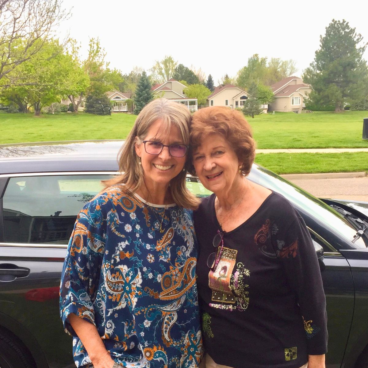 Kathleen and her mom outside in front of a car. 