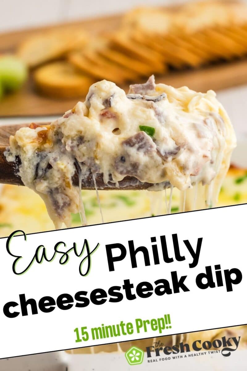 A wooden spoon holding a scoop of gooey, cheesy, steak and cheese dip, for pinning.