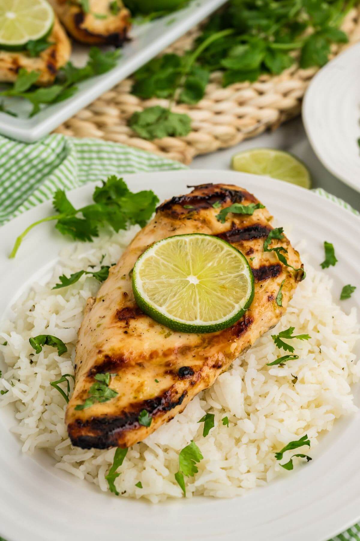 A circle slice of lime is centered on top of a grilled chicken breast over cilantro rice.