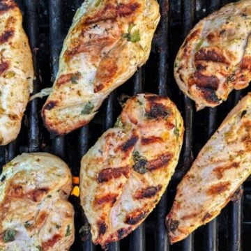 Tender chicken breasts sit on a grill.