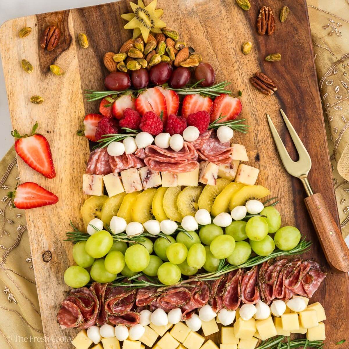 Overhead shot of charcuterie in the shape of a Christmas tree on a wooden board.