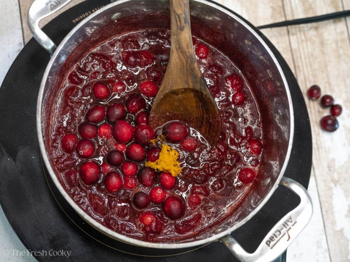 Adding fresh cranberries to the sauce with citrus zest.
