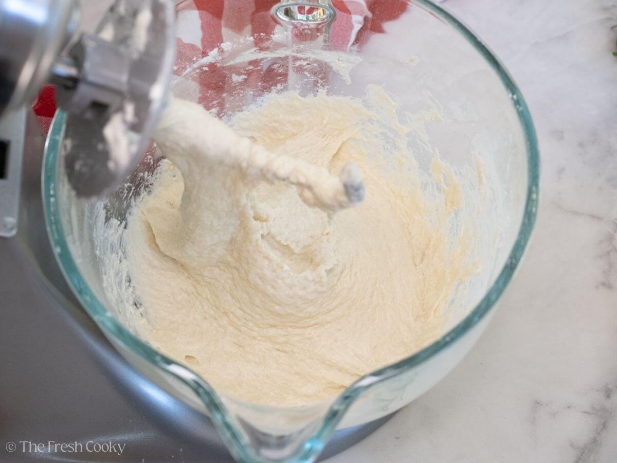 Shaggy dough in a stand mixer bowl with the hook attachment.