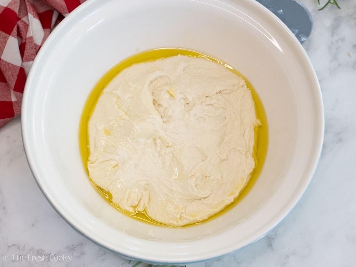 Focaccia dough in a large bowl with olive oil.