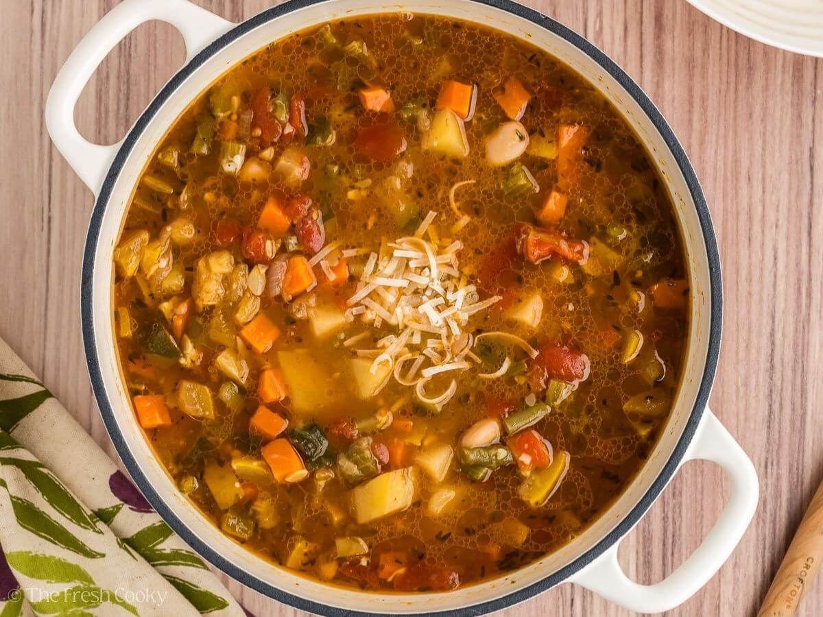 Minestrone soup after it is done cooking and garnished with parmesan cheese.