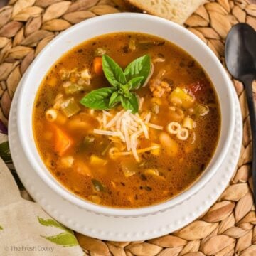 Bowl of minestrone soup served with basil and parmesan on top.
