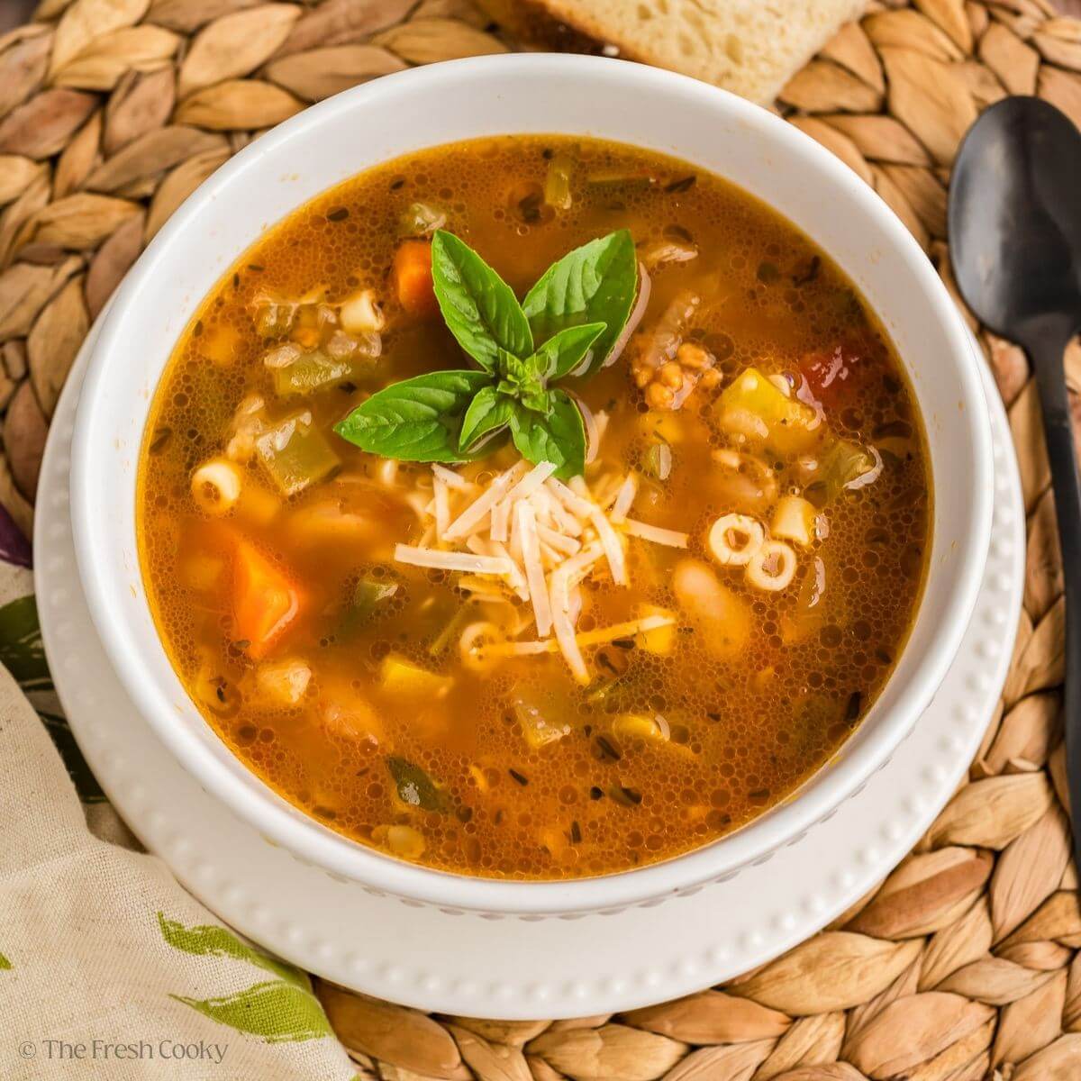Bowl of minestrone soup served with basil and parmesan on top.