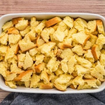 Pieces of torn bread in a buttered casserole dish for French Toast Casserole.
