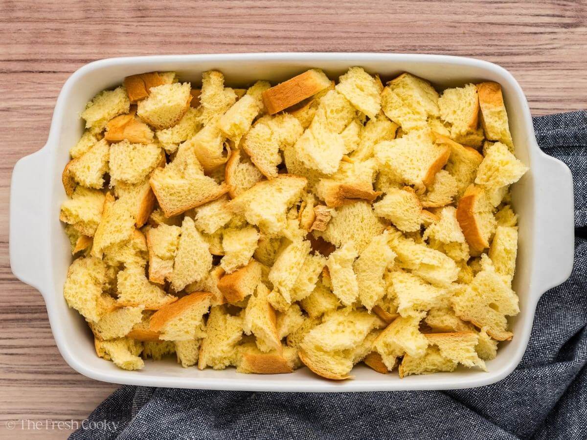 Pieces of torn bread in a buttered casserole dish for French Toast Casserole. 