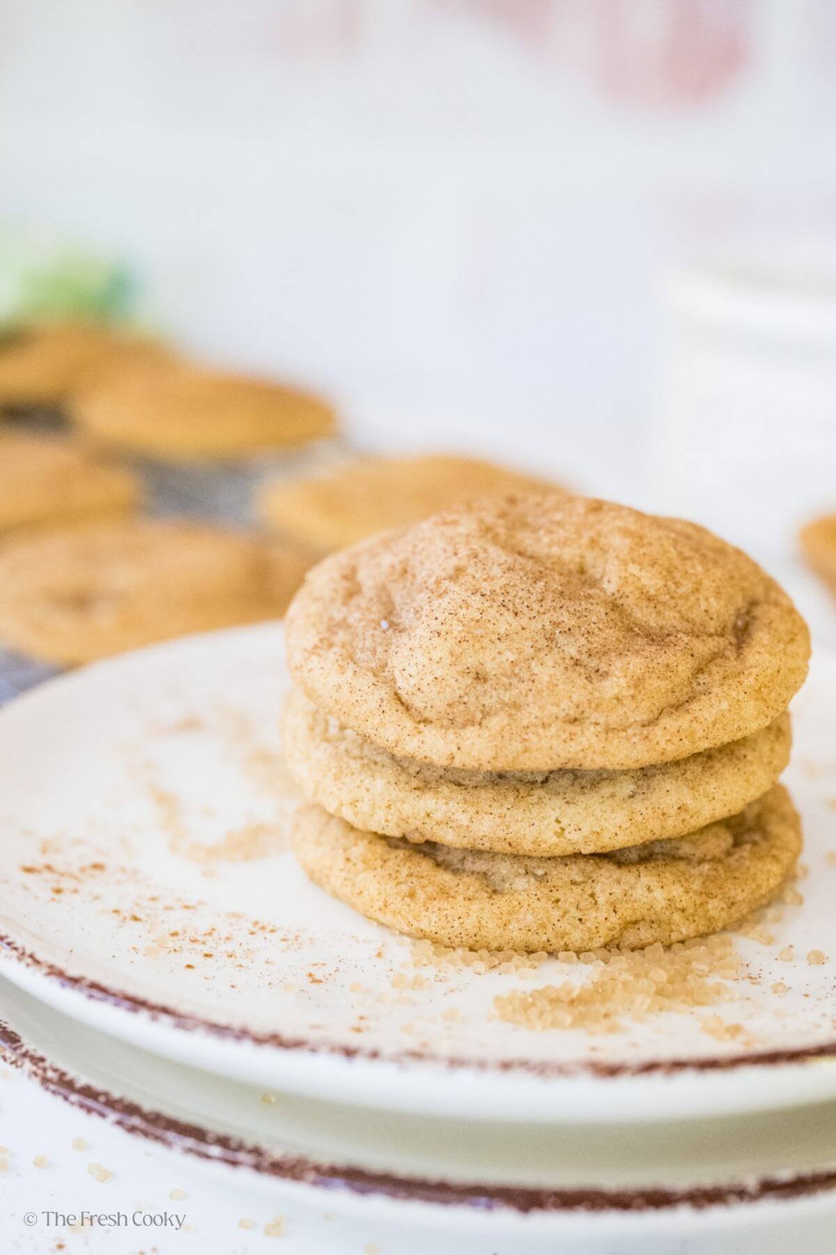 Three snickerdoodle cookies stacked on top of each other on a plate.