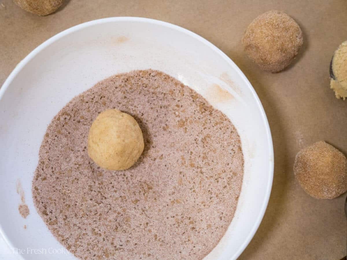 Rolling snickerdoodle dough balls in cinnamon sugar.