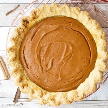 Whole baked sweet potato pie sitting on a wire rack.