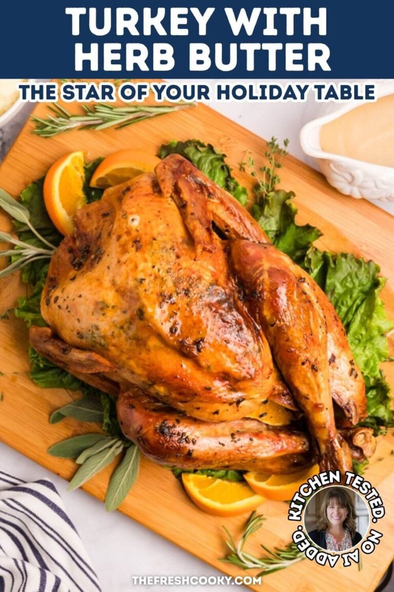 A full, beautifully golden, roasted turkey on a cutting board, surrounded by greens, herbs and oranges, for pinning.