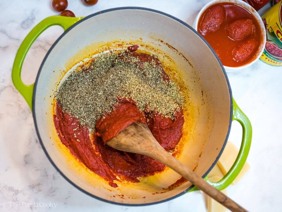 Add herbs and spices to tomato paste in pot. 